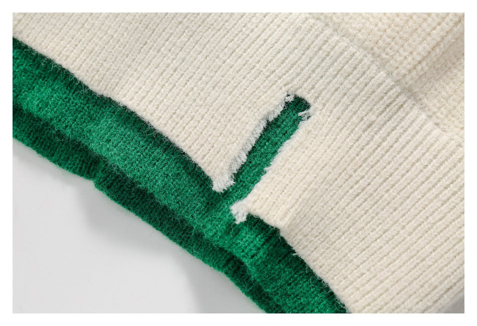 Close-up of ivory rib-knit fabric meeting a thick emerald green knitted trim.