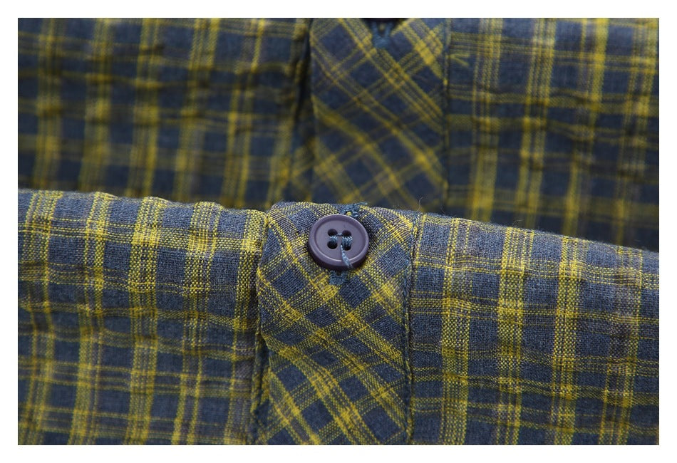 Close-up of a dark button on the blue-gray and mustard plaid shirt.