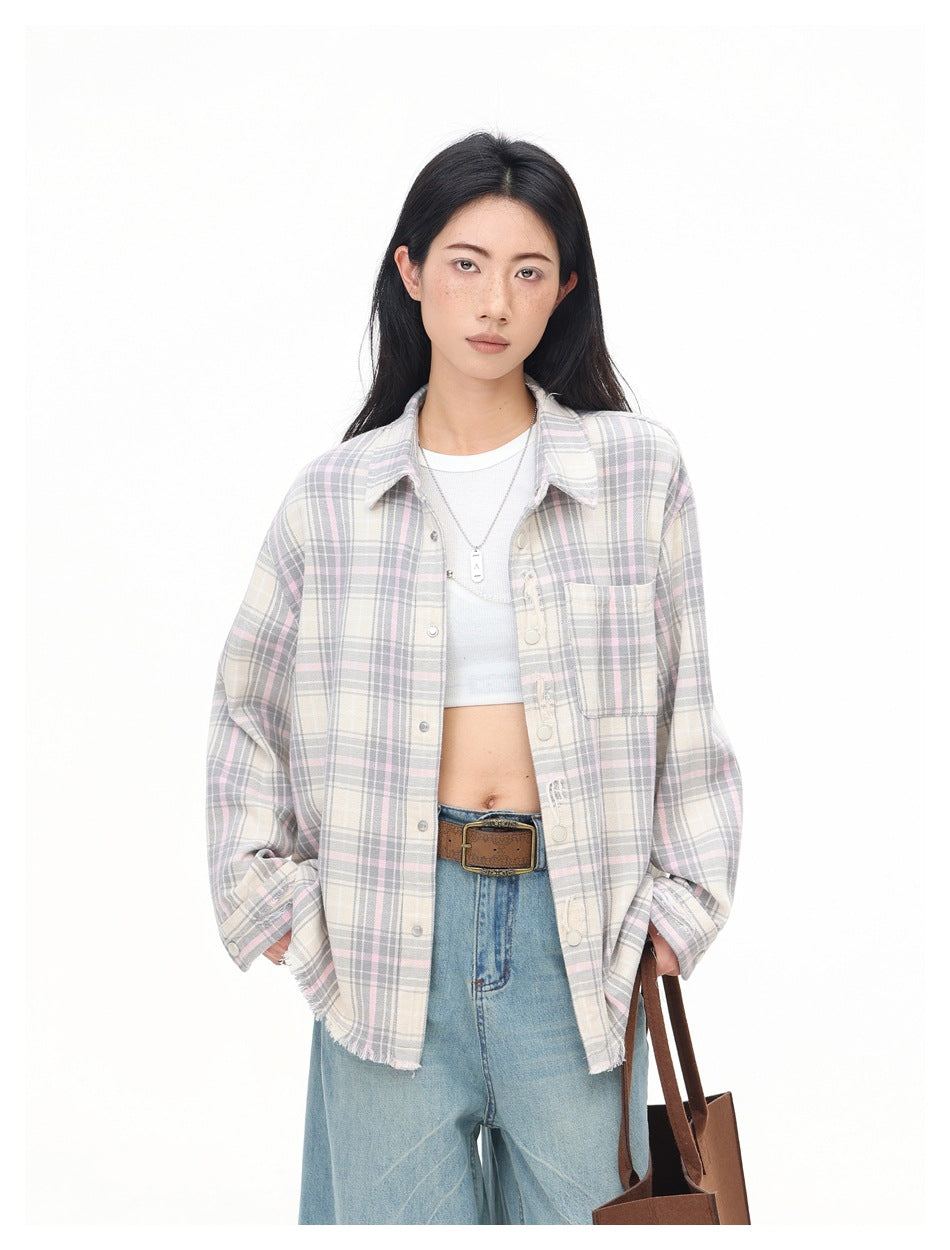 Close-up of model in pink and gray plaid shirt worn open over a white top with a belt and jeans