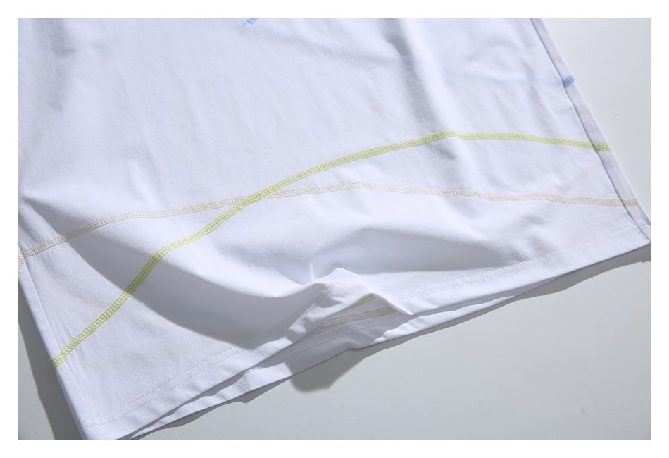 Close-up of the white T-shirt’s lower section with curved pale yellow-green and beige overlock seams.