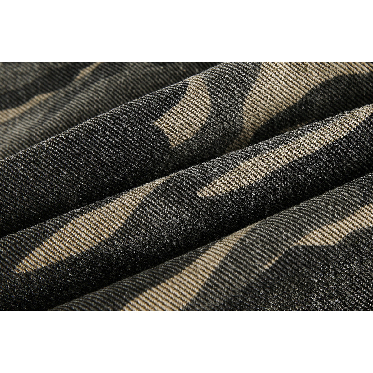 Extreme close-up of the dark gray and tan camouflage fabric, showing its diagonal weave.