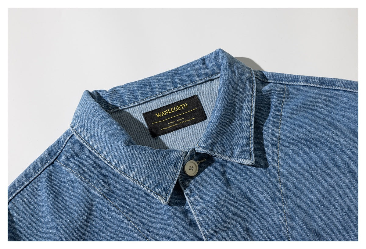 Close-up of the blue denim jacket collar, shoulder seams, button, and black woven neck label.