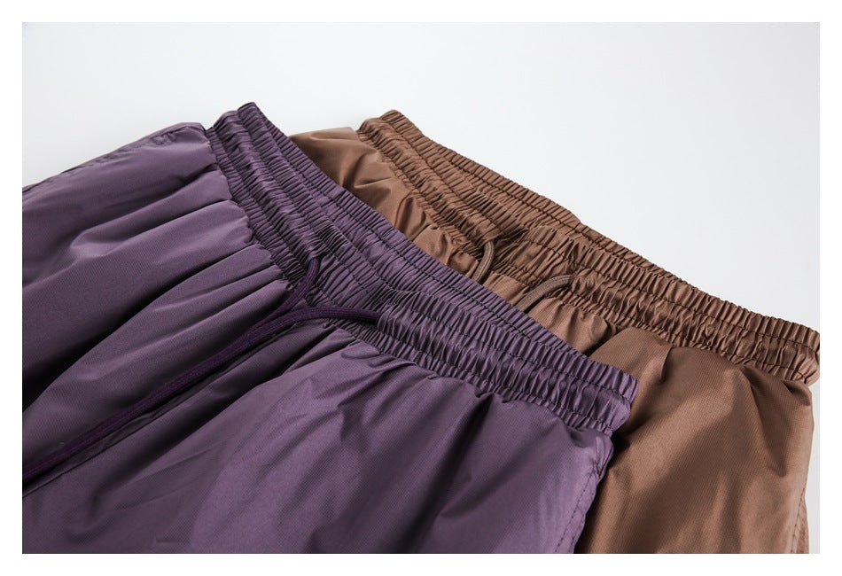 Close view of plum-purple and brown shorts arranged together, showing their gathered elastic waistbands and drawstrings.