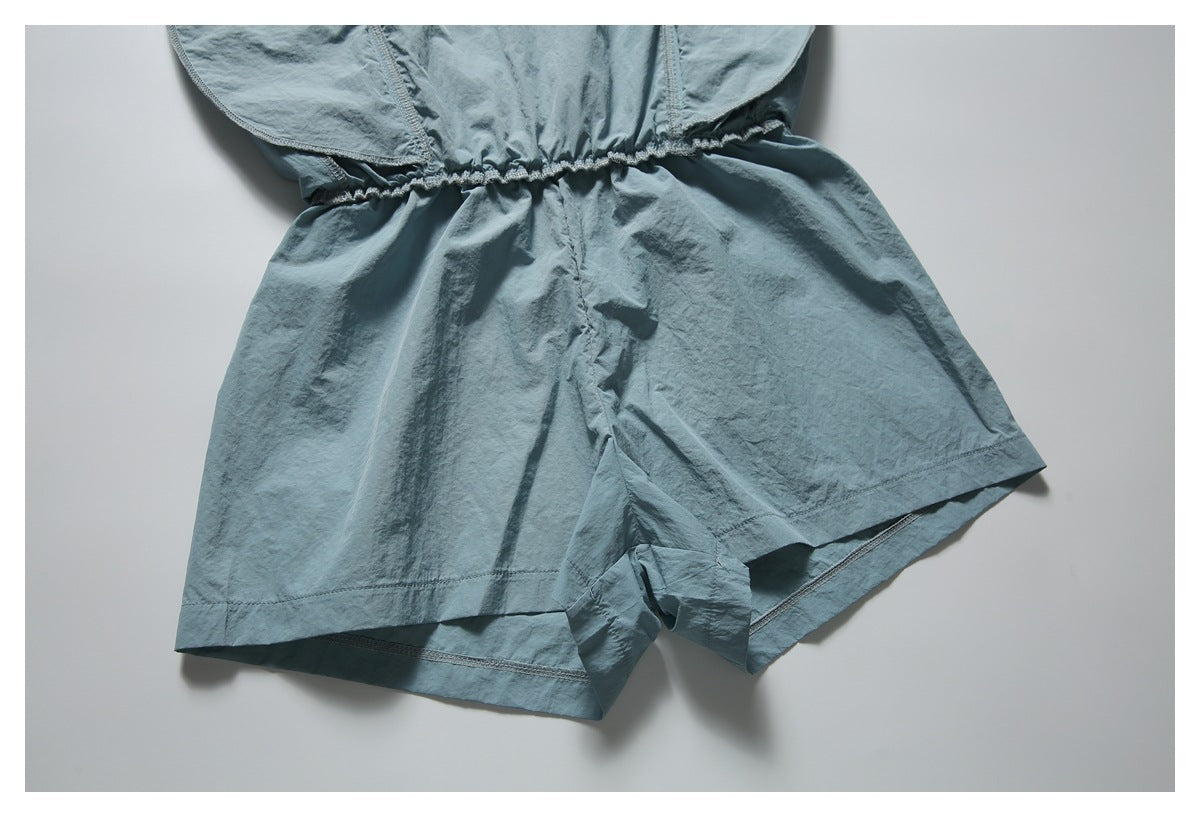 Close-up of the blue-gray romper’s gathered waist and loose shorts legs.