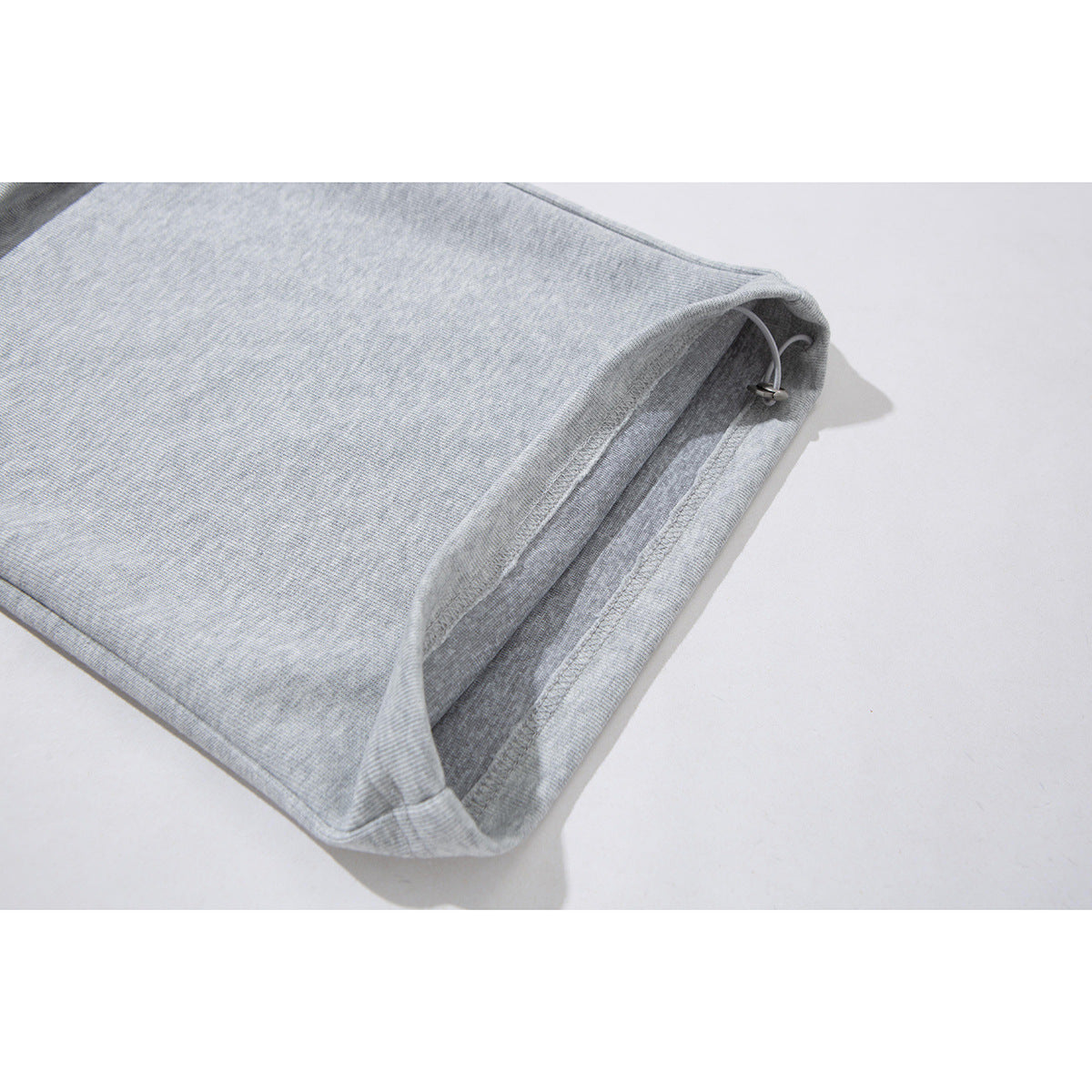 Close-up of the light gray pants hem with an adjustable cord and metal toggle.