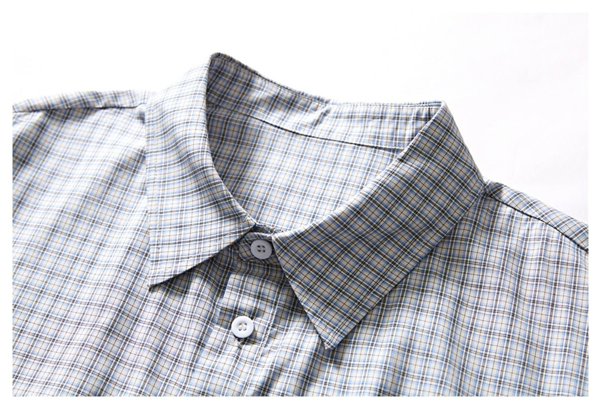 Close-up of the pointed collar and white buttons on a light blue, gray, and tan plaid shirt.