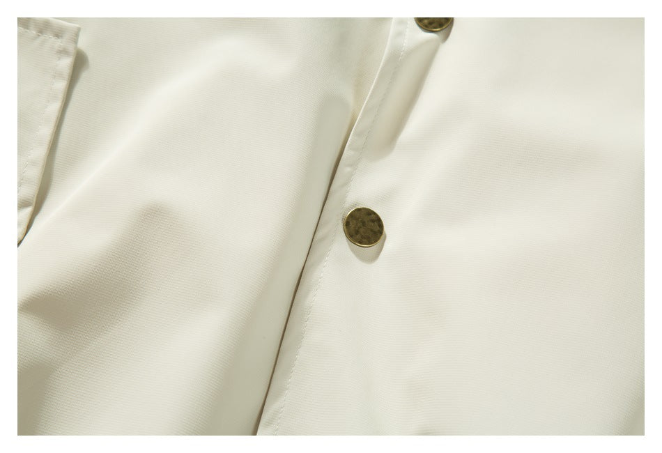 Close-up of ivory fabric and a front placket with an antique-gold button.
