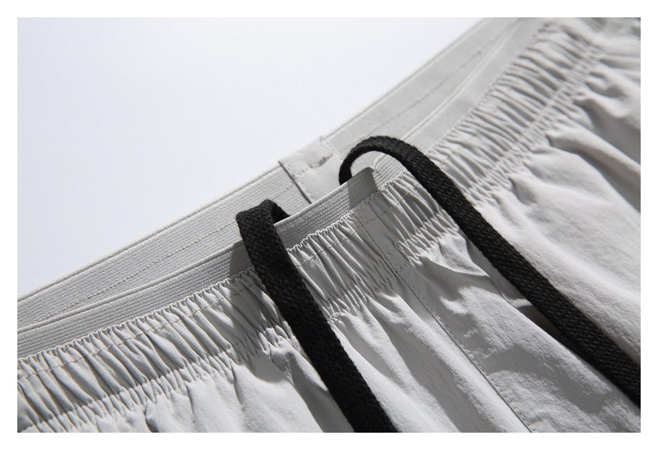 Close-up of the elastic waistband and black drawcords on light gray shorts.