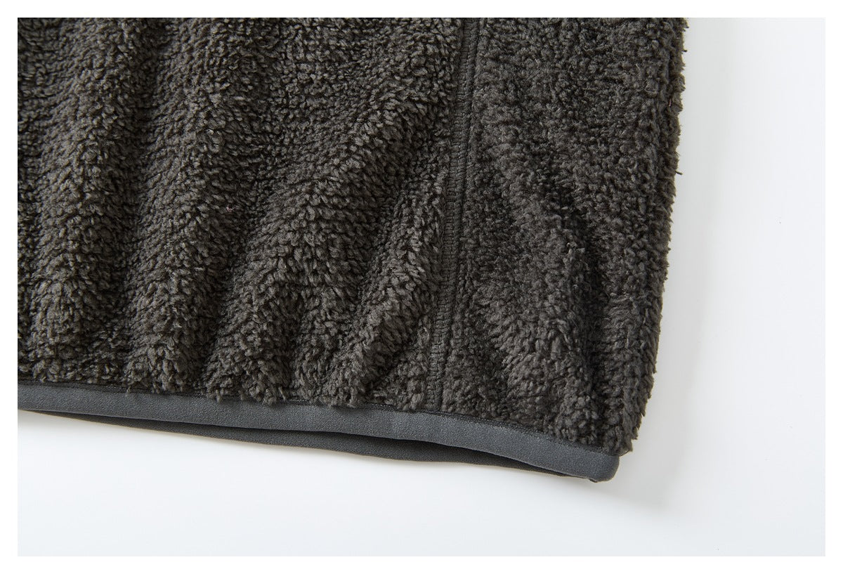 Close-up of the charcoal fleece jacket hem with dark gray binding and a vertical seam.
