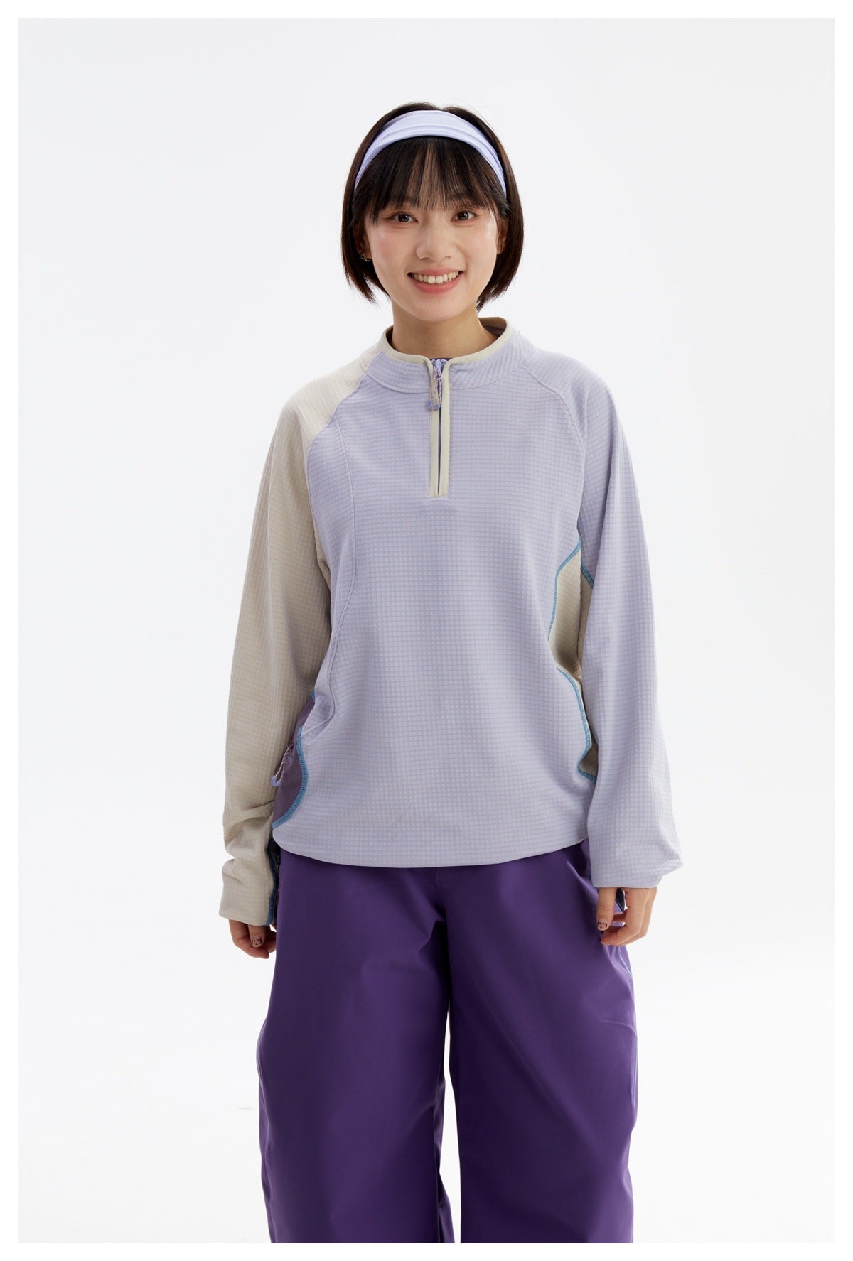 Front view of a model wearing a lavender and cream half-zip pullover with purple pants.