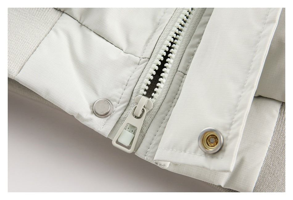 Close-up of a white jacket's chunky zipper, zipper pull, and metal snap fasteners.