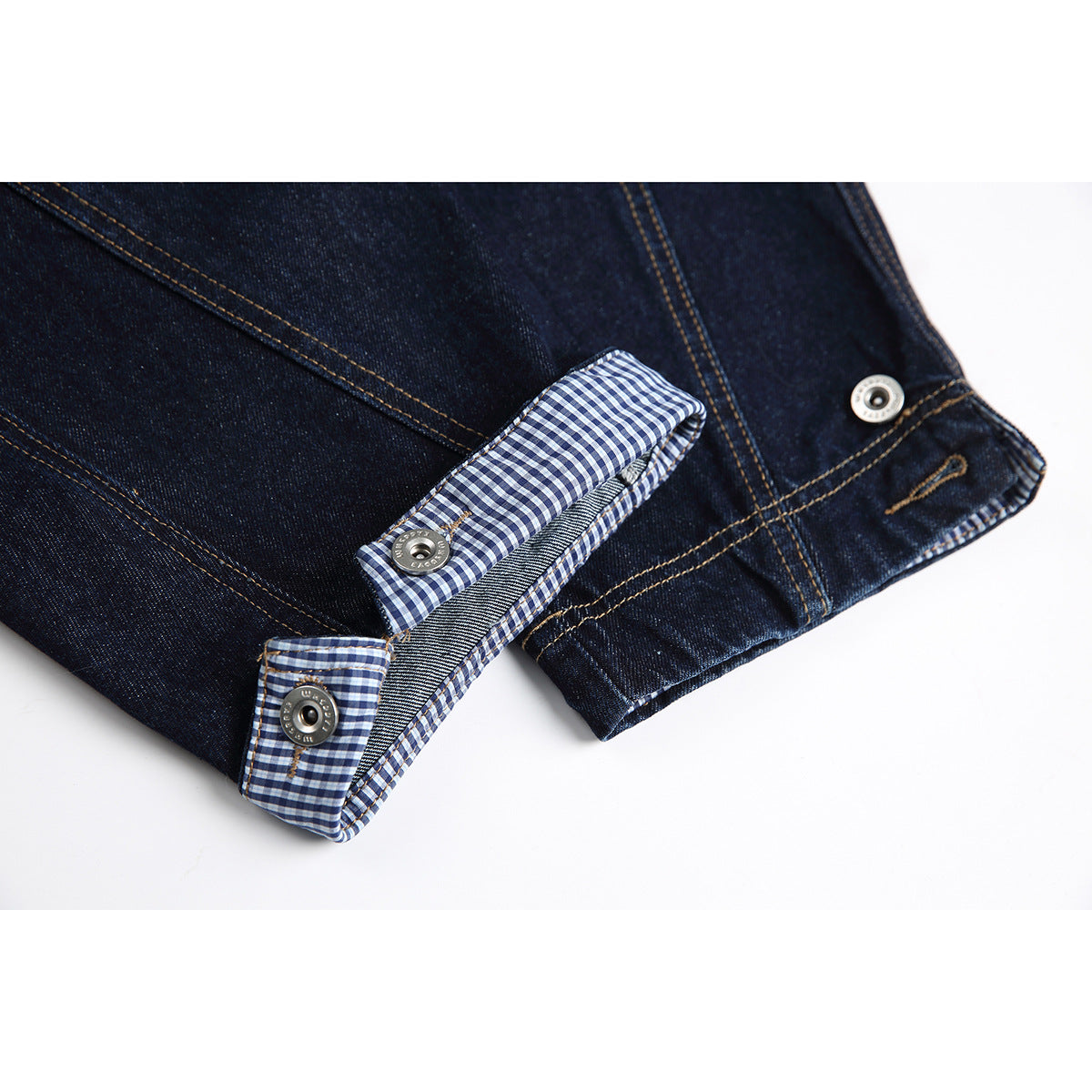 Close-up of dark indigo denim cuffs with blue-and-white gingham lining and metal snap buttons.