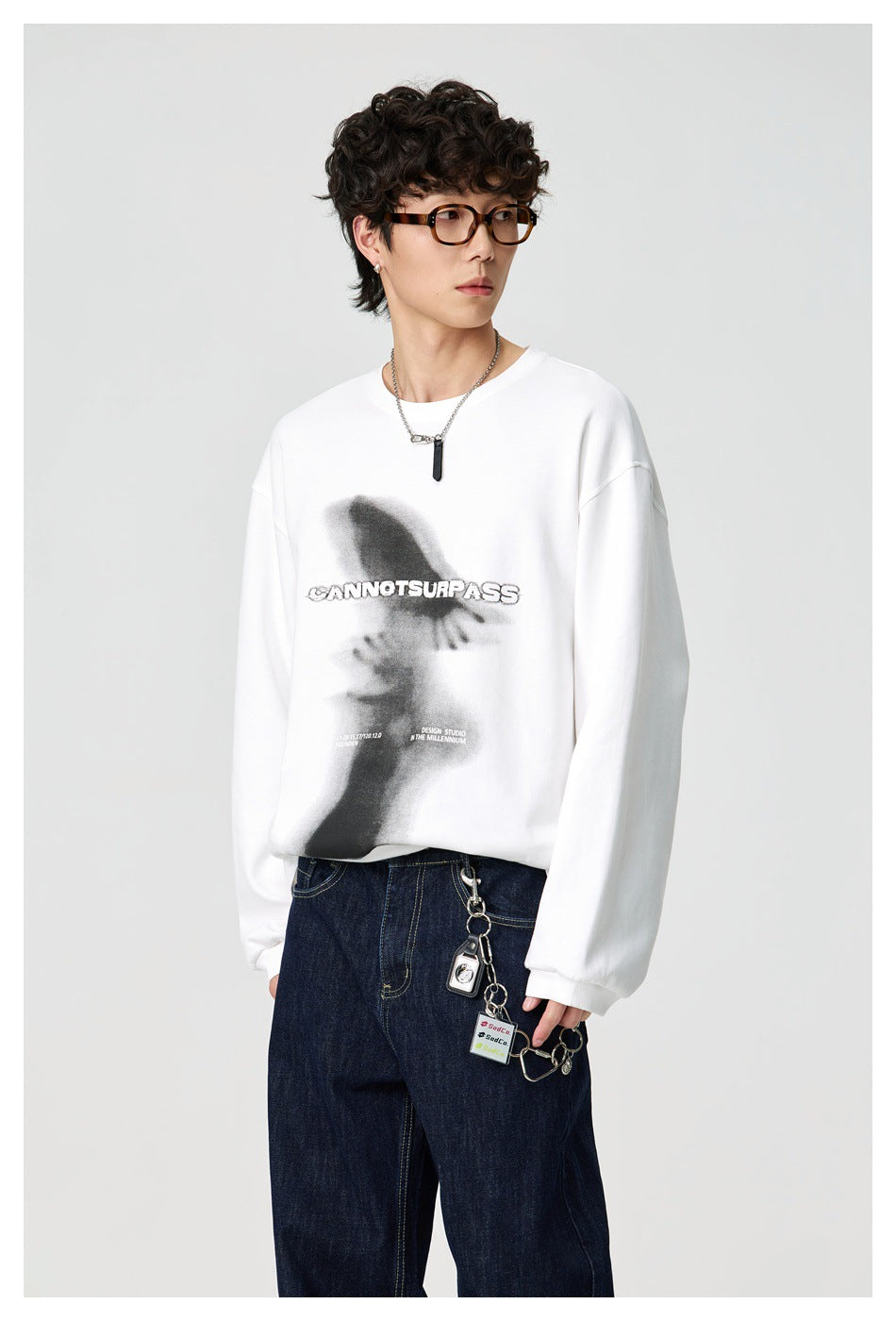 Model wearing the white long-sleeve graphic top with dark jeans, three-quarter front view