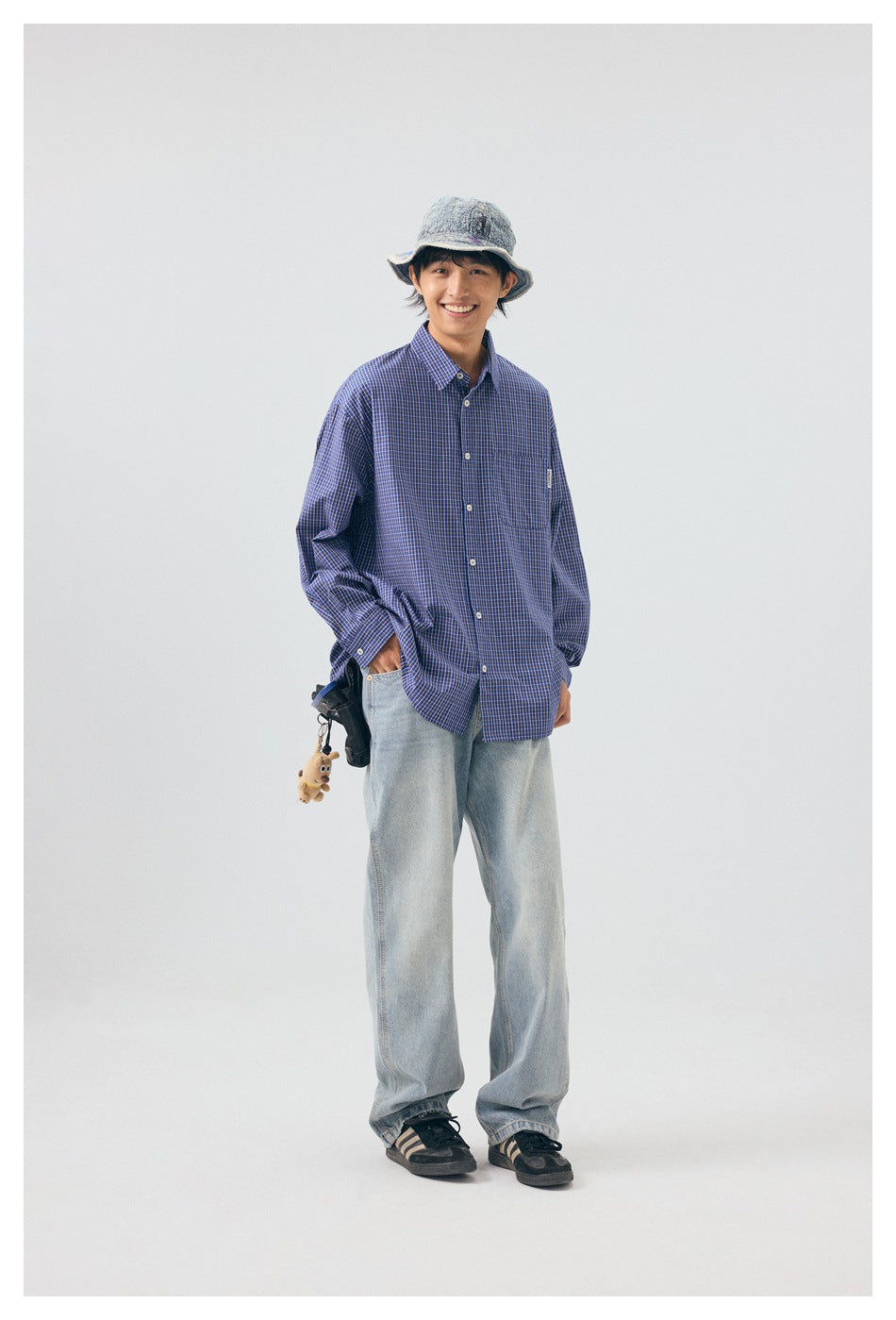 Model smiling in a blue checked button-up shirt with a chest pocket, shown from the front.