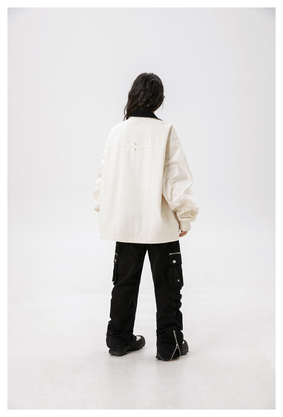 Model viewed from behind wearing an oversized ivory jacket with a black collar and gathered sleeves.