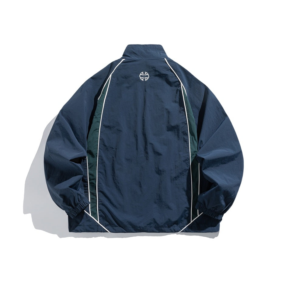 Back view of a navy zip-up jacket with dark green side panels, white piping and a small upper-back emblem.