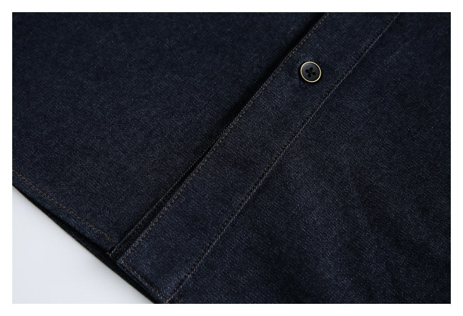 Close-up of dark indigo denim with a single dark button on a stitched placket.