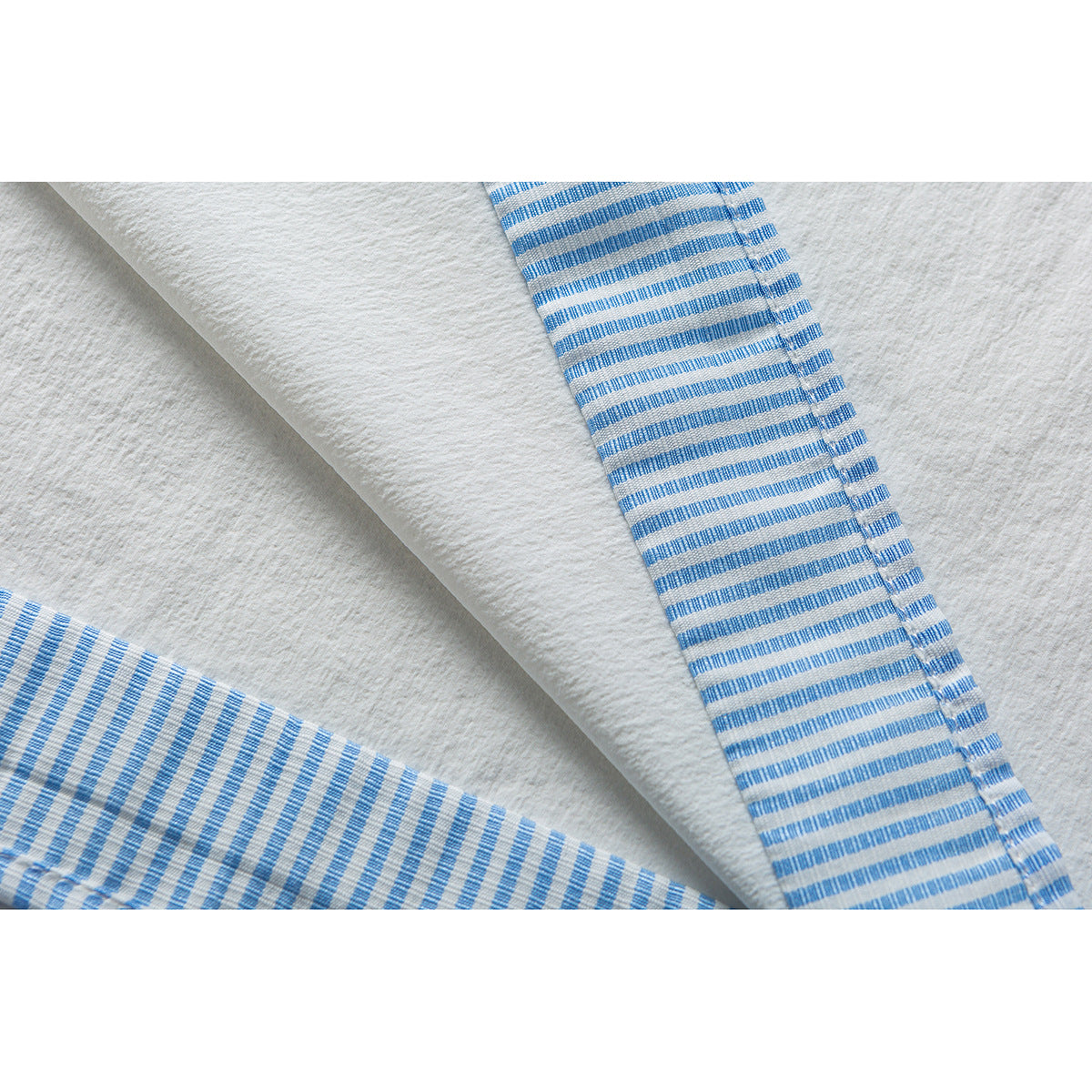 Close-up of a white shirt with blue-and-white striped trim along the opening and edge.