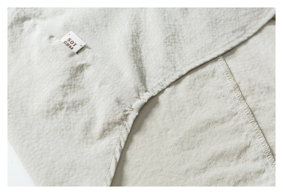 Close-up of a seam and small woven label on light beige garment fabric.