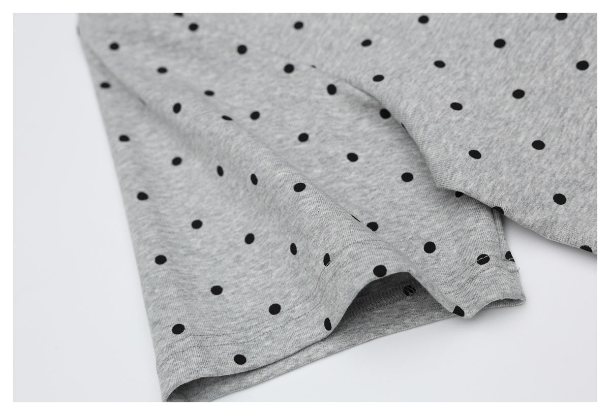 Close-up of the gray shirt's black dot pattern and stitched sleeve hem.