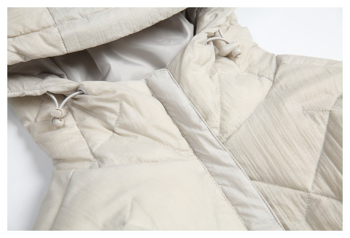 Close-up of a cream quilted jacket with a drawcord toggle and overlapping front placket.
