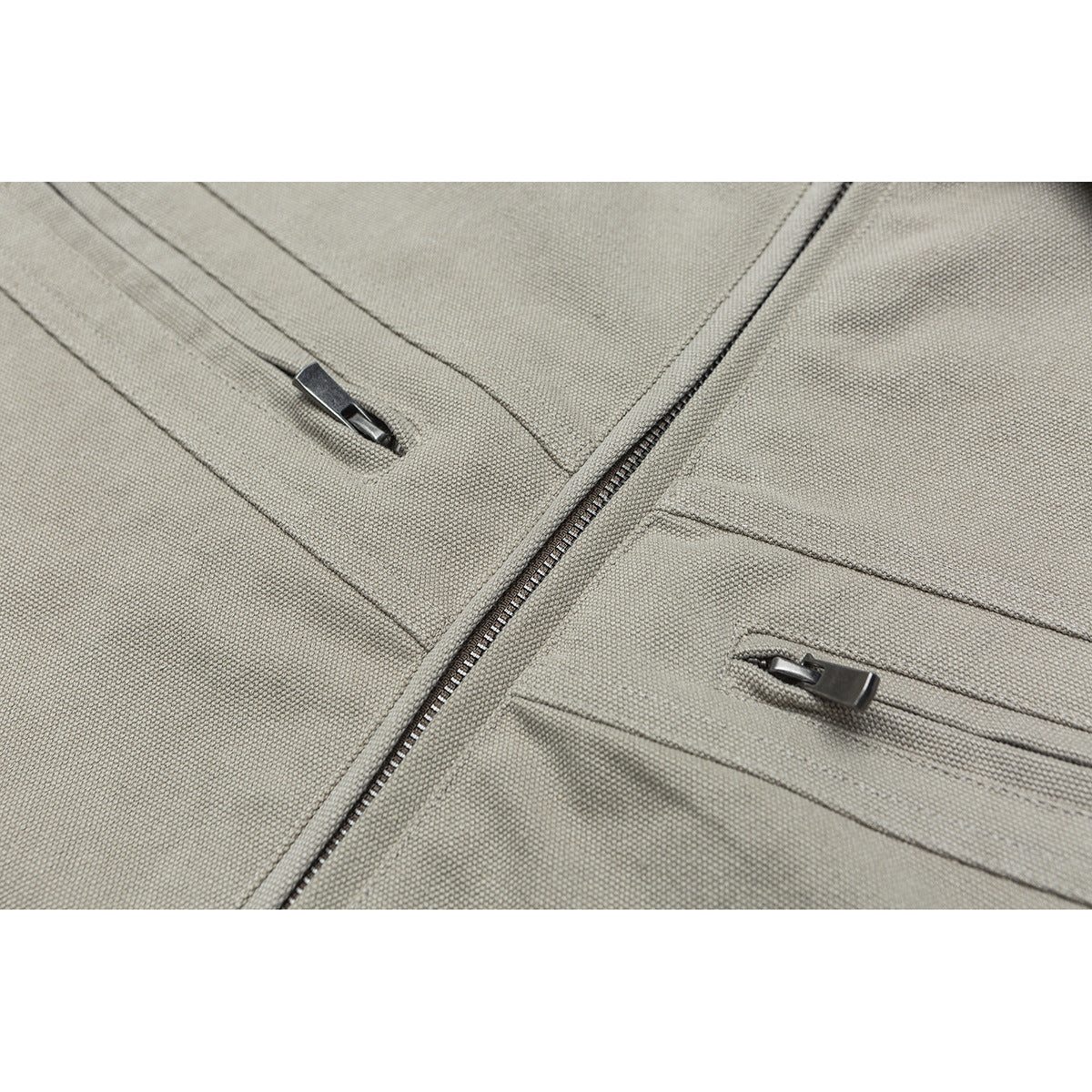 Close-up of a beige jacket showing the main zipper and two slim zippered pockets.