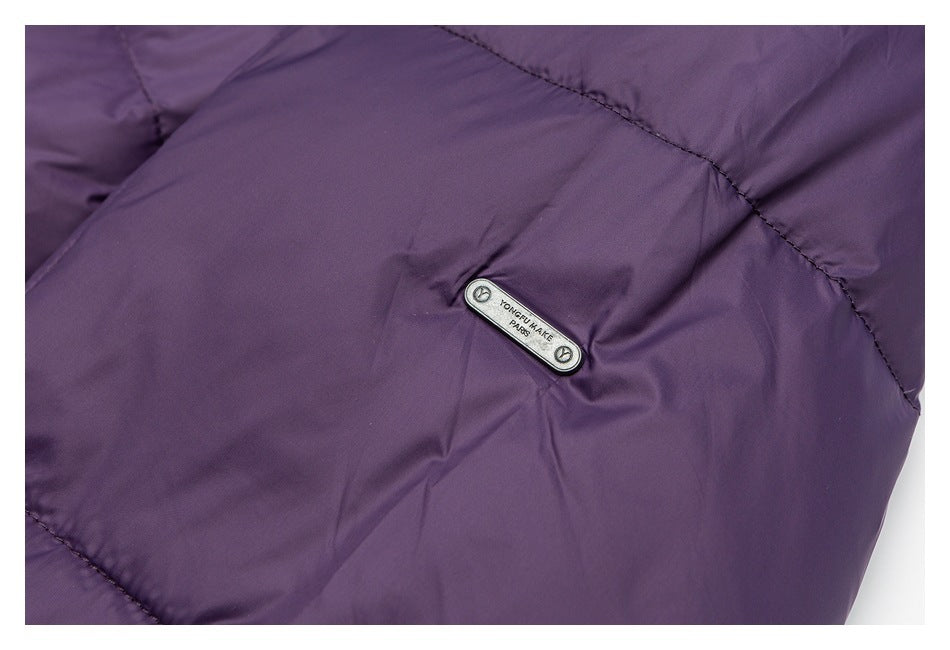 Close-up of a small metal brand plate on deep purple quilted jacket fabric.