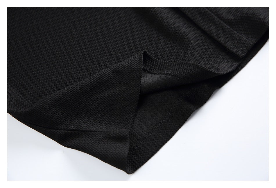 Close-up of the black garment's folded hem and stitched seam against a white background.