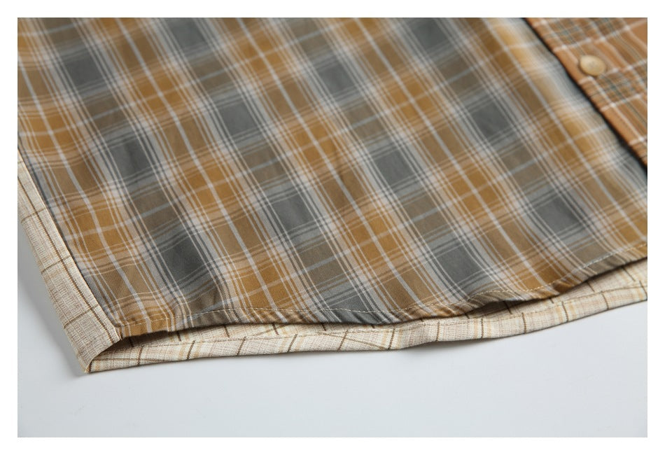 Close-up of the curved hem and stitched edge of a gray and camel plaid shirt.