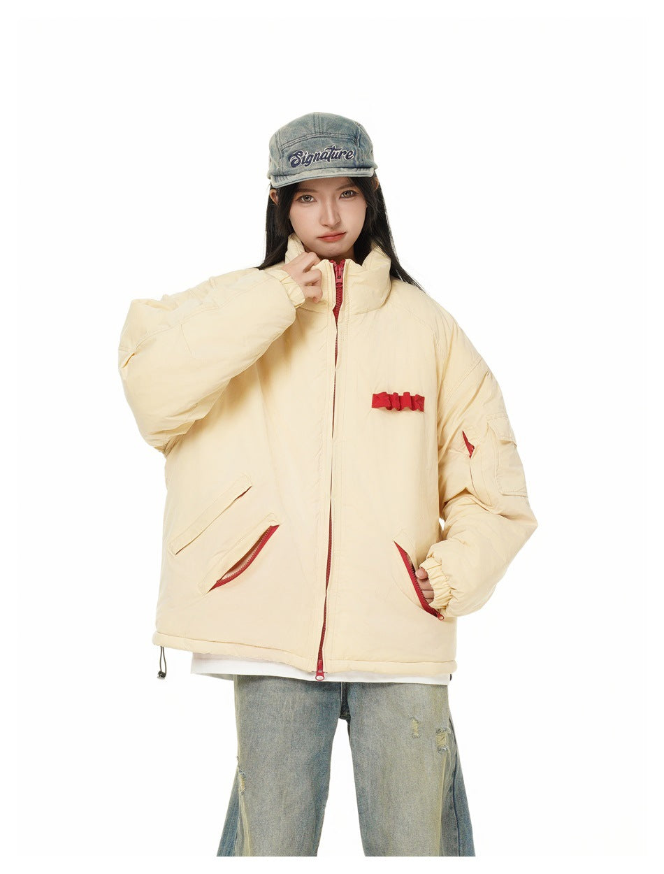Model in oversized beige puffer jacket showing red zippered pockets, chest bow trim and sleeve pocket
