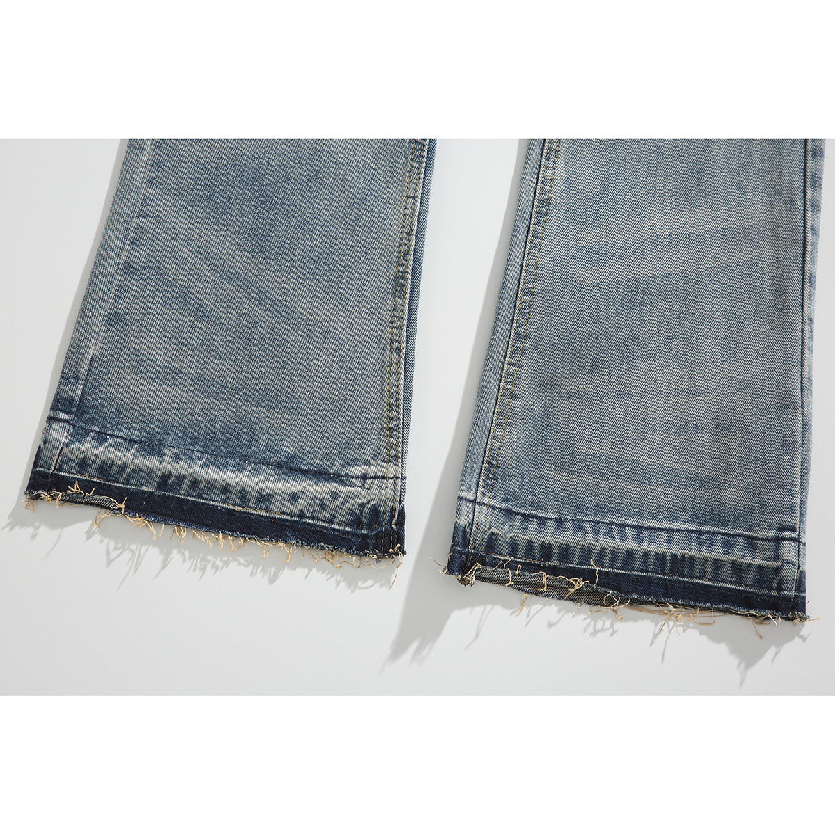 Close-up of the jean legs showing faded hems with frayed, unfinished edges.