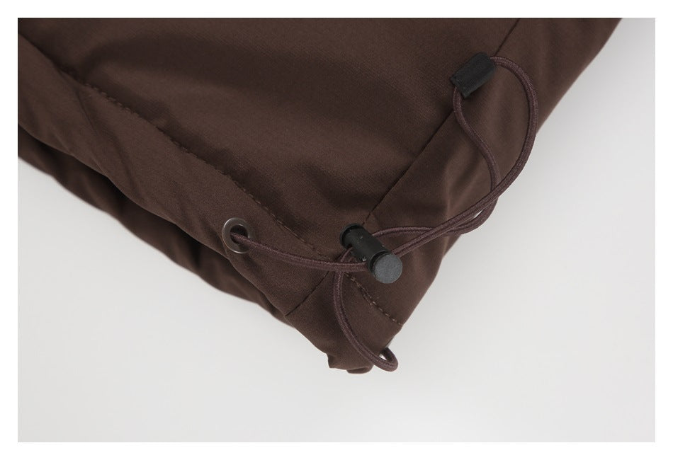 Close-up of a dark brown jacket hem drawcord, grommet, and black cord lock.