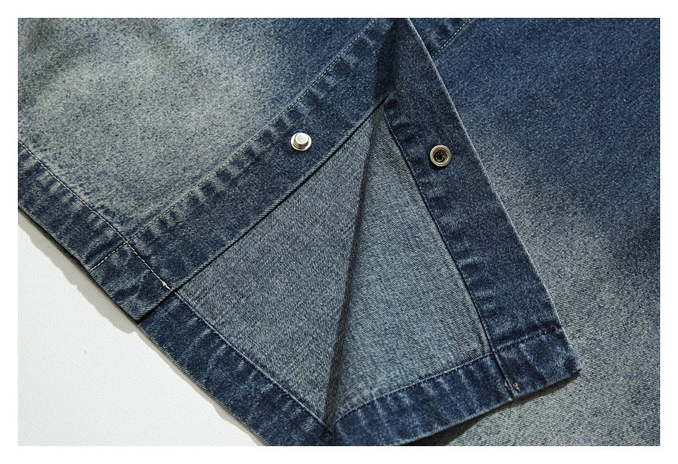 Close-up of a blue denim jacket opening with two metal snap fasteners and a folded inner panel.