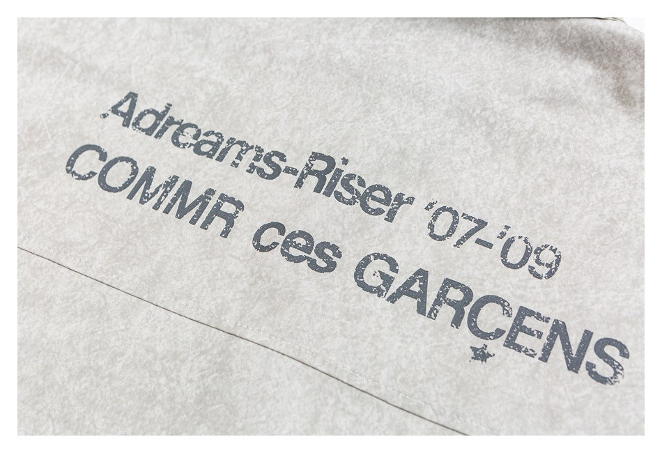 Light beige mottled garment detail with distressed dark English lettering printed on the fabric.