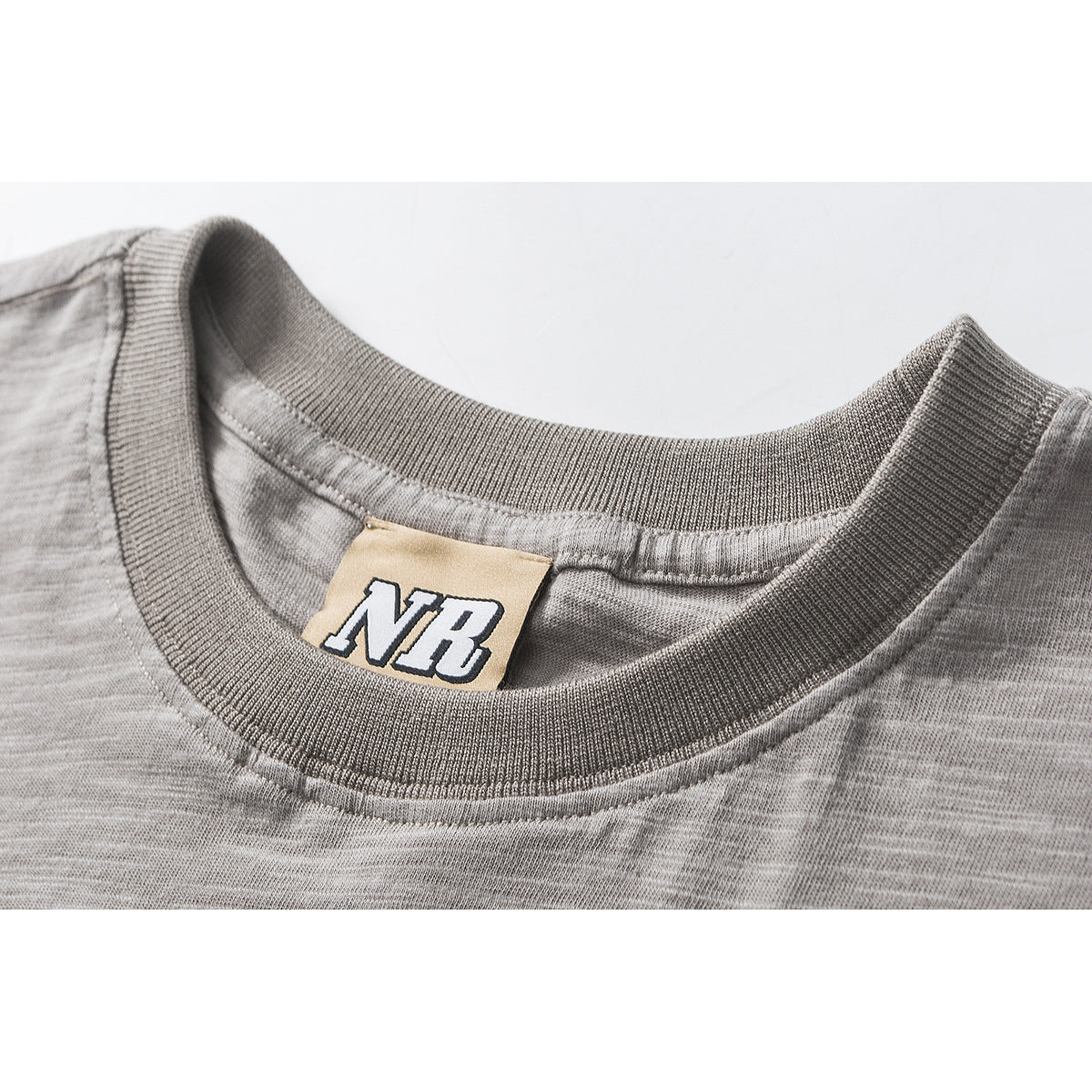 Close-up of a gray marled T-shirt's ribbed crew neckline and sewn NB neck label.
