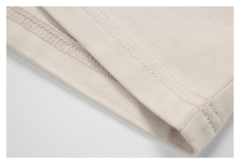 Close-up of beige garment hem with overlock stitching and a double-stitched seam.