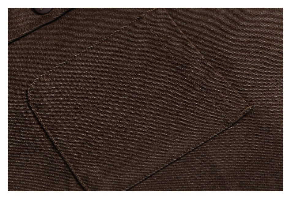 Close-up of a brown shirt's stitched chest pocket and fine diagonal fabric texture.