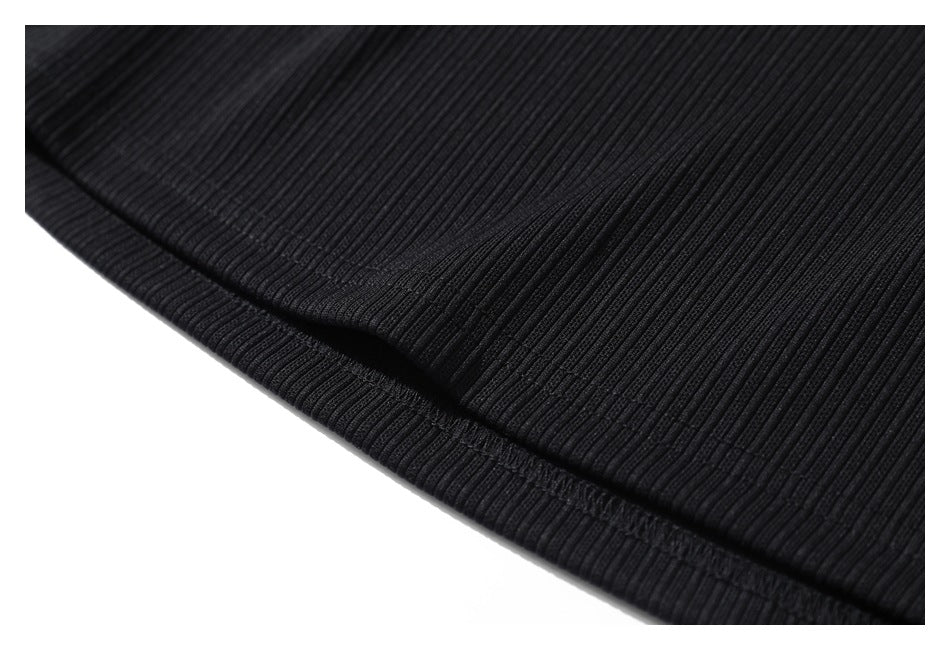 Close-up of the black ribbed garment's folded hem and stitching.