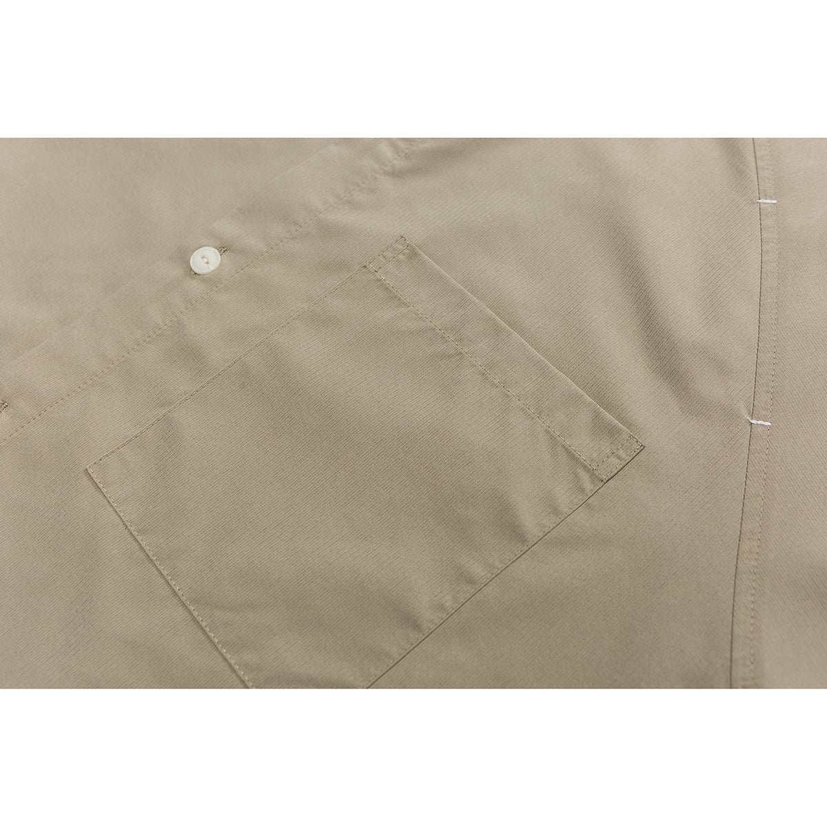 Close-up of a taupe shirt’s angled chest pocket, button, and stitching.