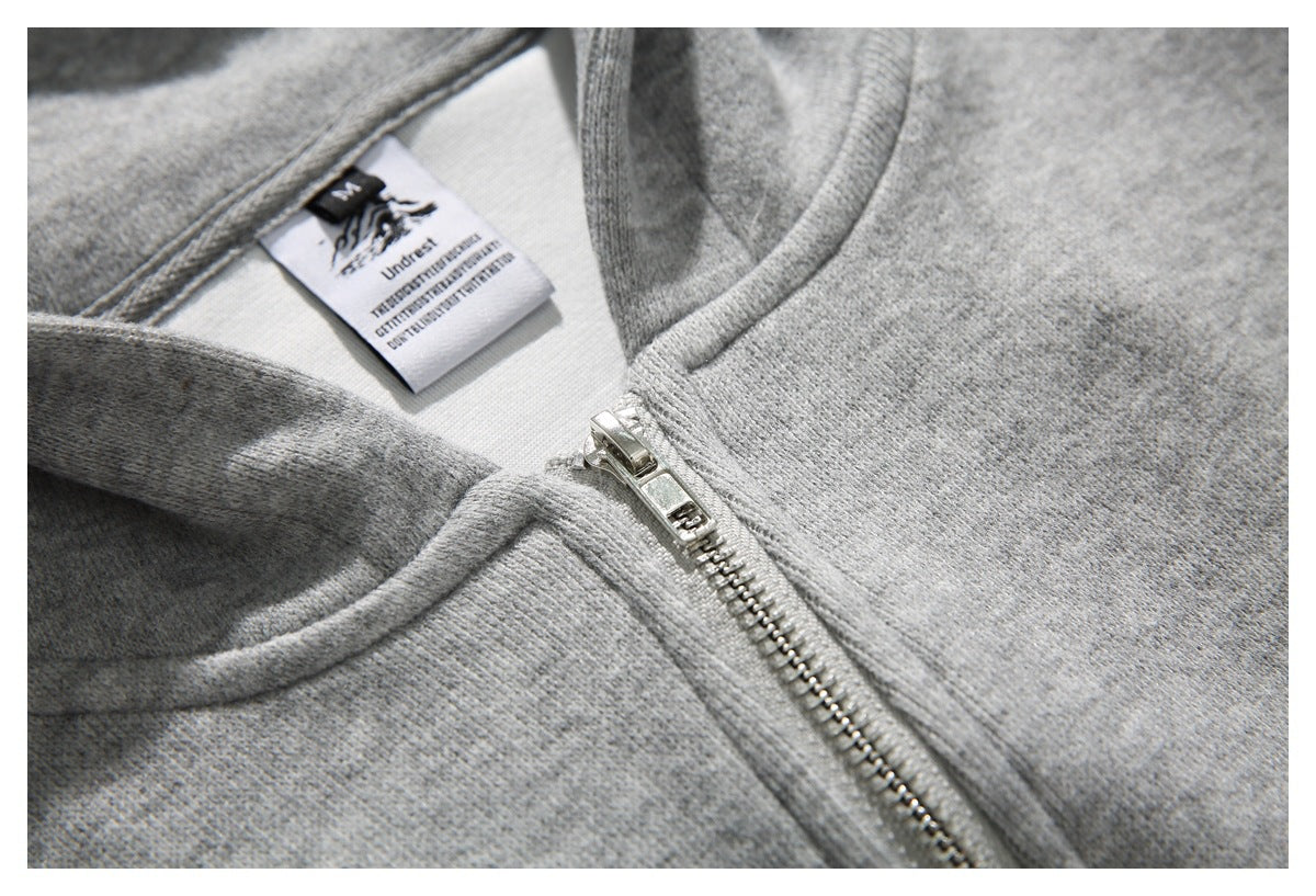 Close-up of a light gray hoodie's metal zipper, neckline, and sewn label.