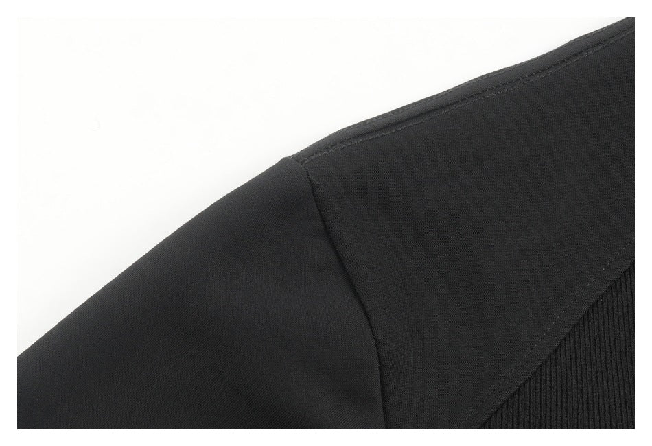 Close-up of a black garment seam beside a ribbed fabric panel.