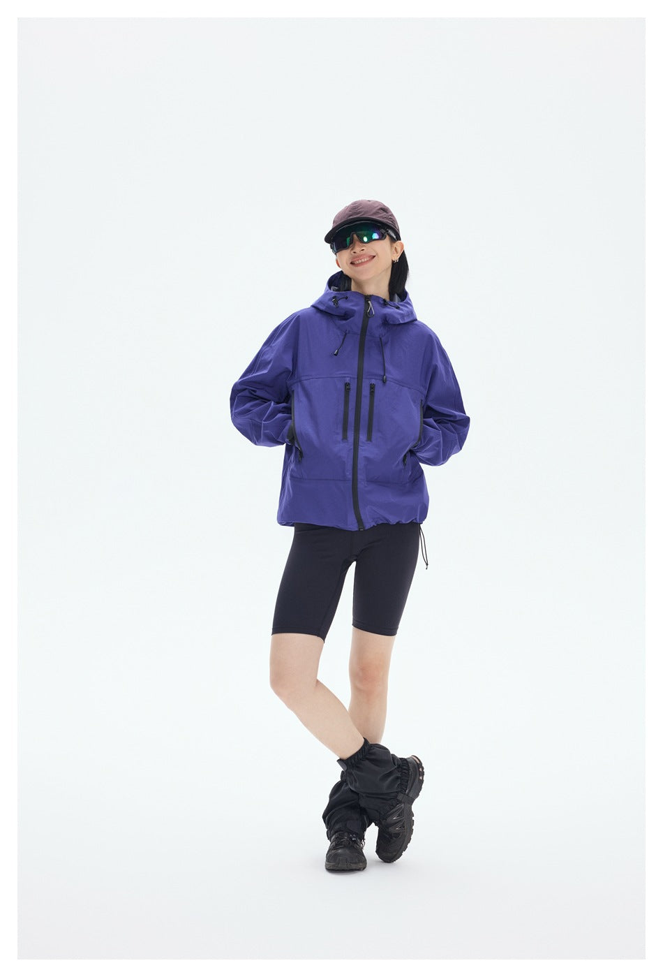 Full-length front view of a model wearing a purple hooded jacket with black zip pockets and black shorts.