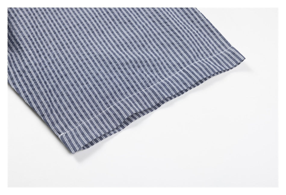 Close-up of the blue-gray shirt's striped fabric and stitched bottom hem.