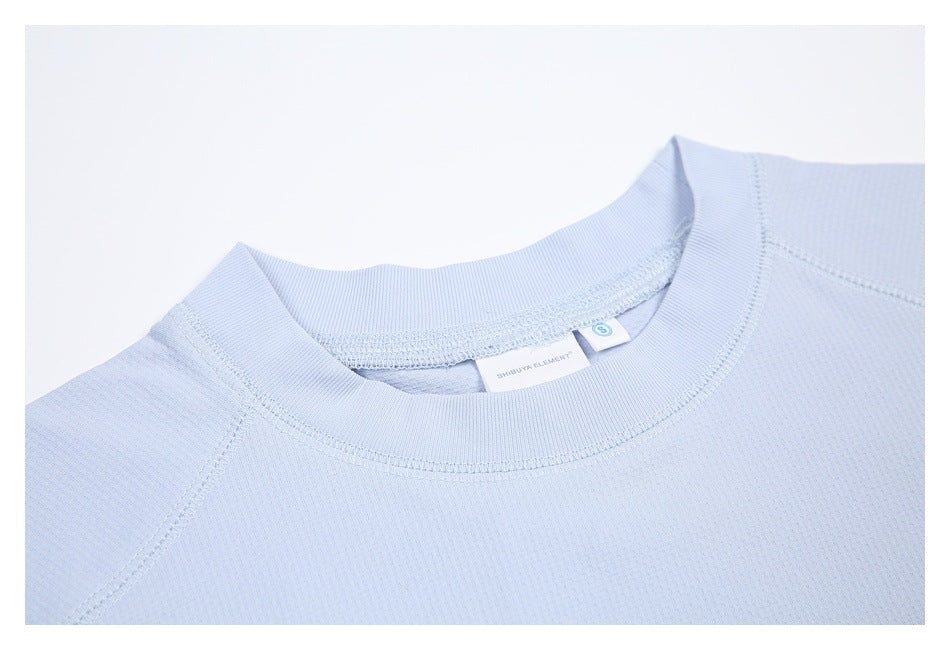 Close-up of the pale blue shirt's ribbed crew collar, stitching, and attached neck labels.