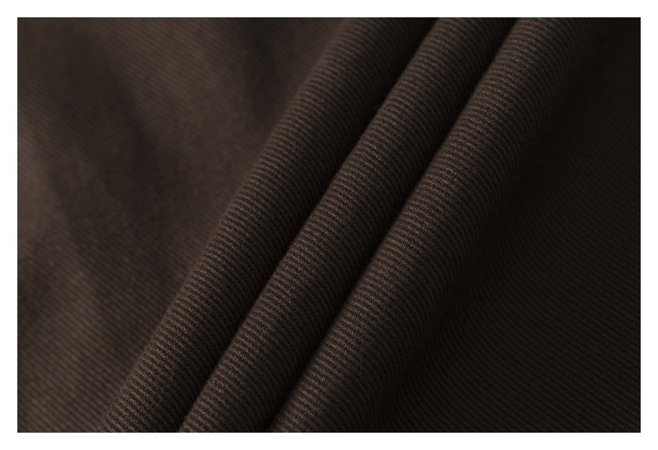Close-up of dark brown fabric folded into ridges, showing its fine diagonal weave.