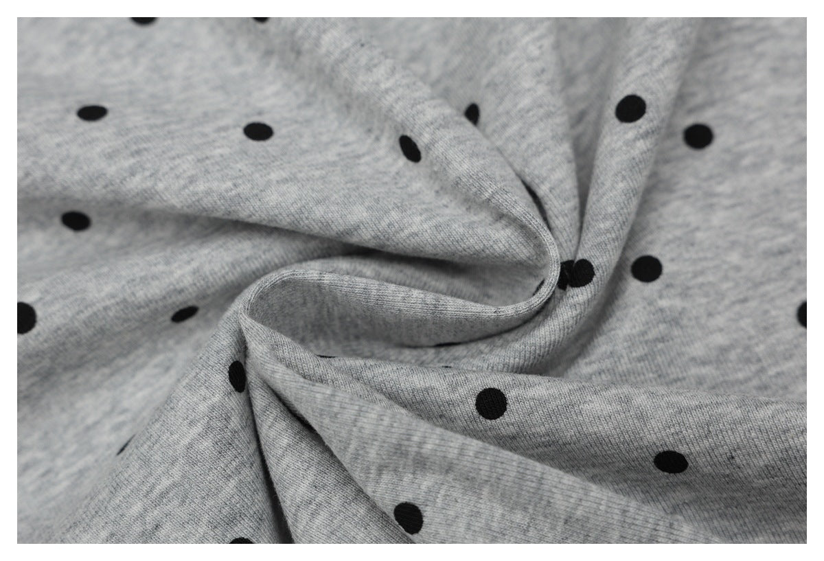 Close-up of heather gray fabric with black polka dots, gathered into soft folds.