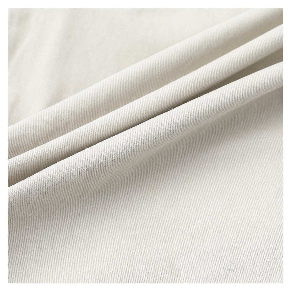 Close-up of light beige fabric folded into ridges, showing its fine diagonal weave.