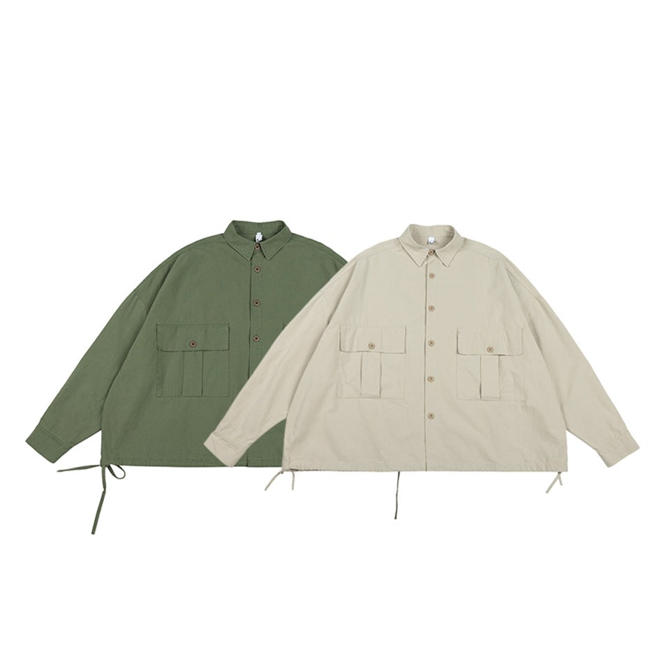 Two oversized button-up utility jackets displayed front-facing: one in muted green and one in light beige.