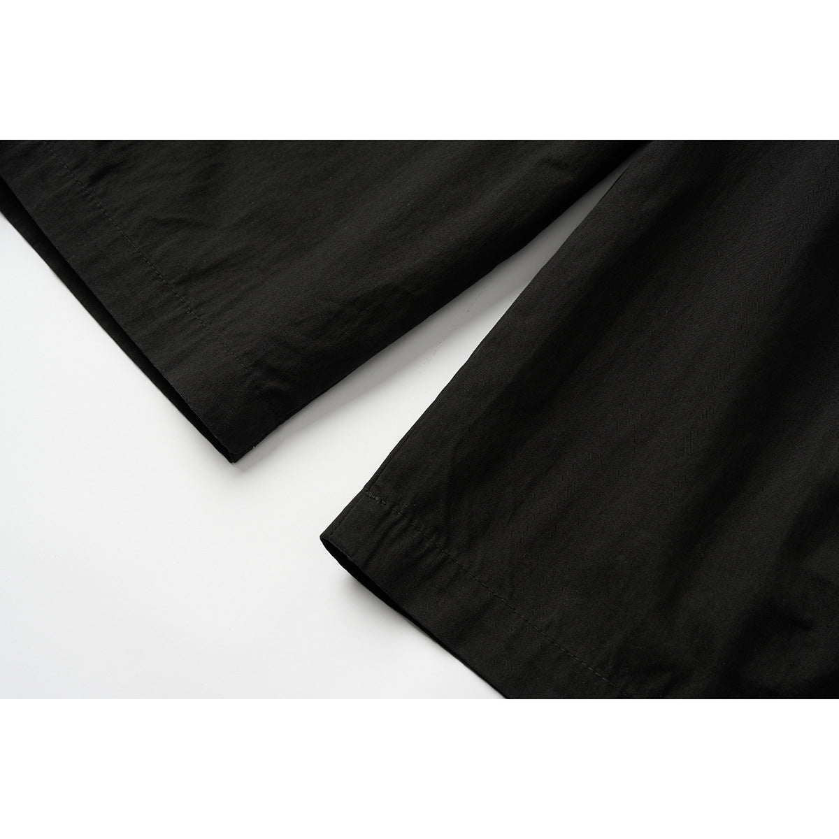 Close-up of the black pants' wide legs and stitched hems.