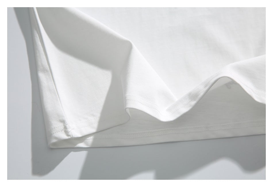 Close-up of the white shirt’s double-stitched hem and draped fabric.